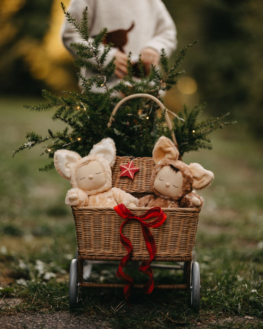 Close up of a child holding a wicker basket with the Olli Ella Fawny Dozy dinkum dolls inside