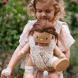 A child carrying a Dinkum doll using the Olli Ella Garden Floral Gardenia print Dinkum Dolls Quilted Toy Carrier.