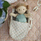 A Dinkum Doll laying in the Olli Ella Garden Floral Gardenia print Dinkum Dolls Quilted Carry Cot 