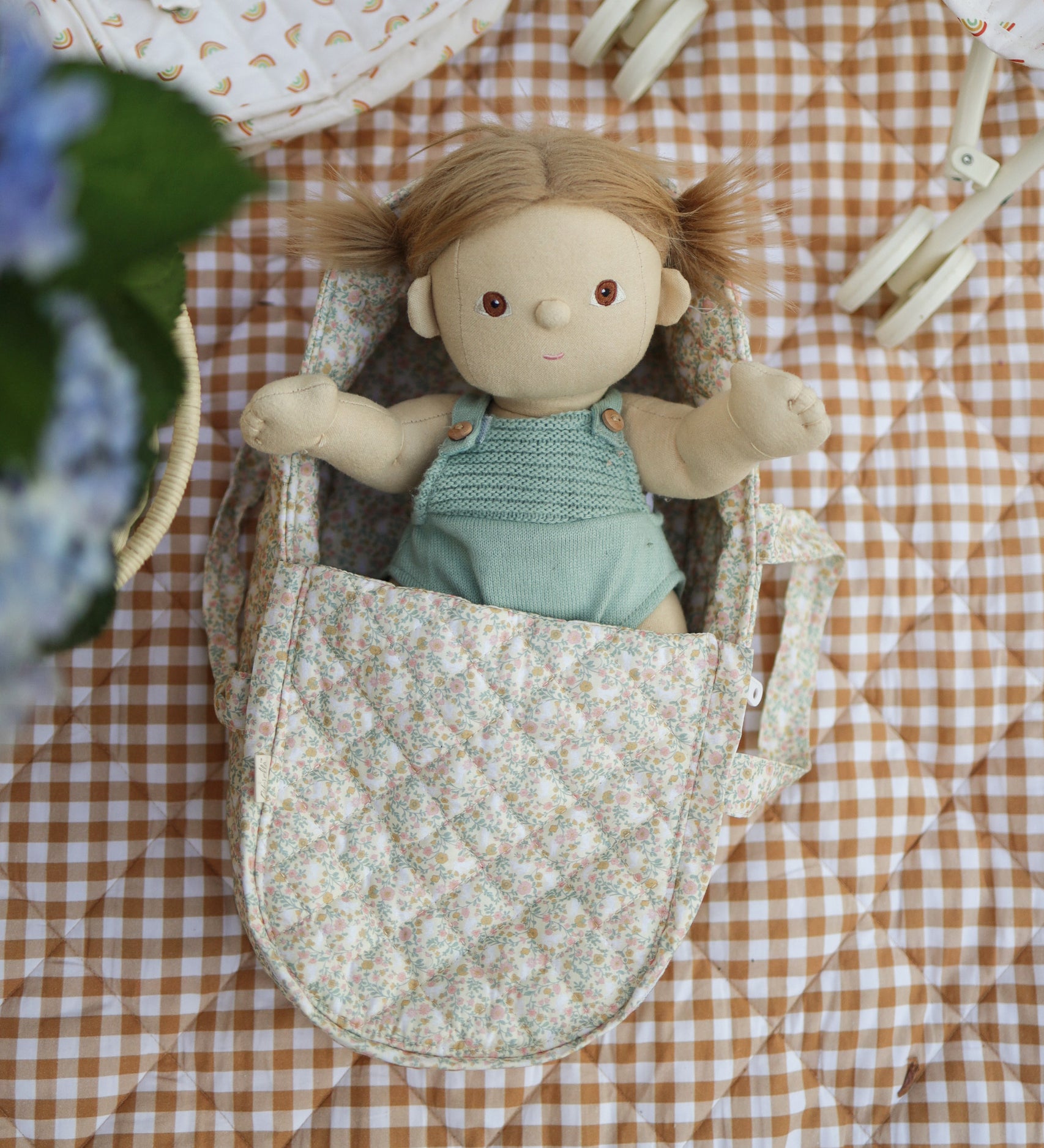 A Dinkum Doll laying in the Olli Ella Garden Floral Gardenia print Dinkum Dolls Quilted Carry Cot 