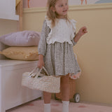 A child holding the Olli Ella Garden Floral Gardenia print Dinkum Dolls Quilted Carry Cot in their hand by the straps. 