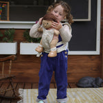 A child carrying a Dinkum doll using the Olli Ella Garden Floral Gardenia print Dinkum Dolls Quilted Toy Carrier.