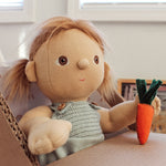 An Olli Ella Gigi Dinkum doll holding a felt carrot sitting in a home made cardboard high chair. 