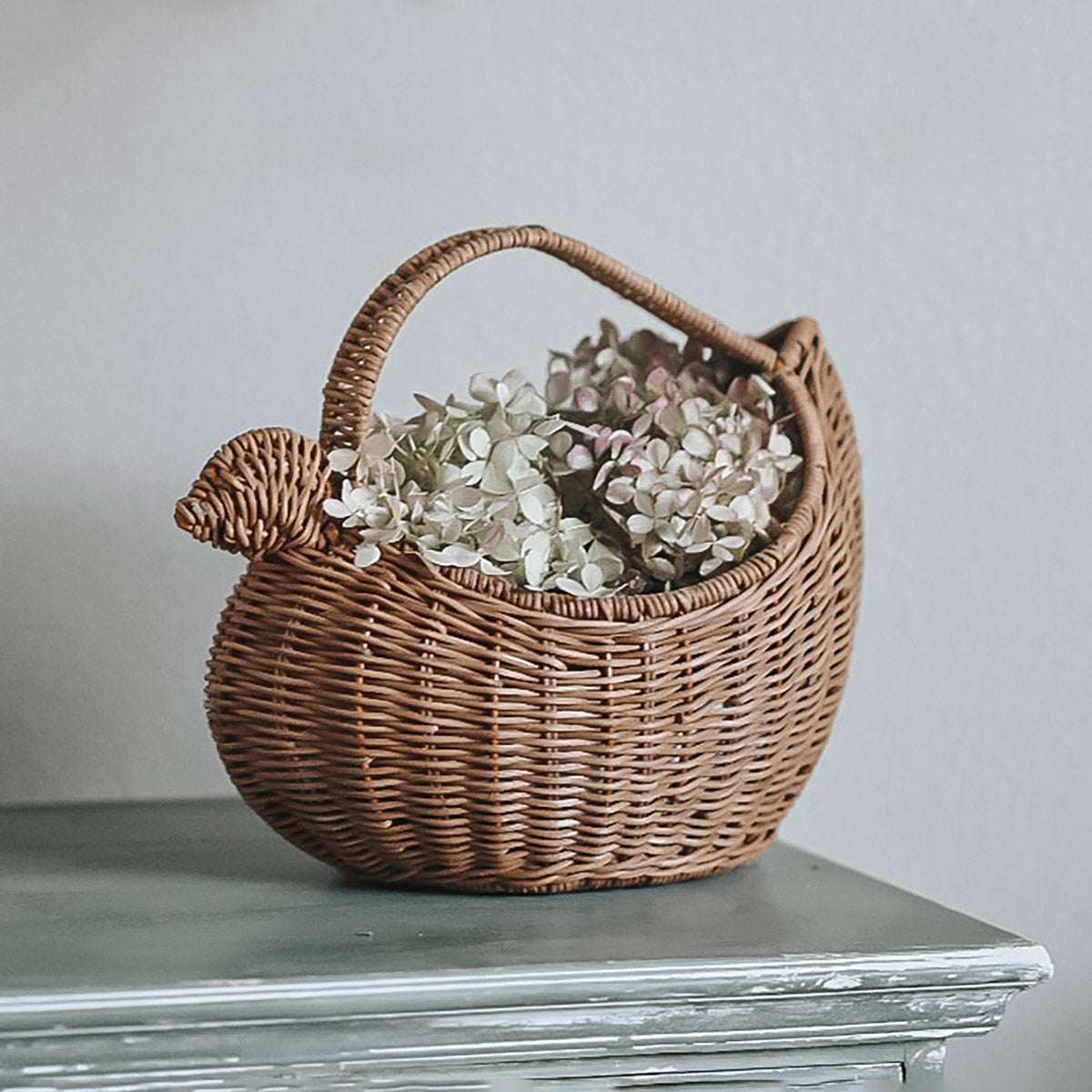 Child stood holding the Olli Ella plastic-free rattan chicken basket