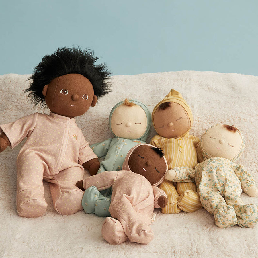 Olli Ella daydream collection dozy dinkum dolls laying on a white blanket next to a dinkum doll dress in the daisy print pjs