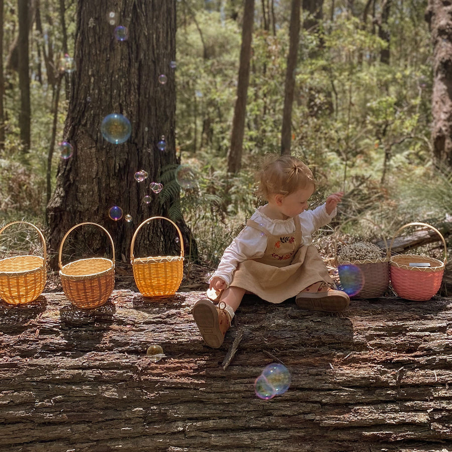 Close up of child holding 2 Olli Ella berry blossom baskets