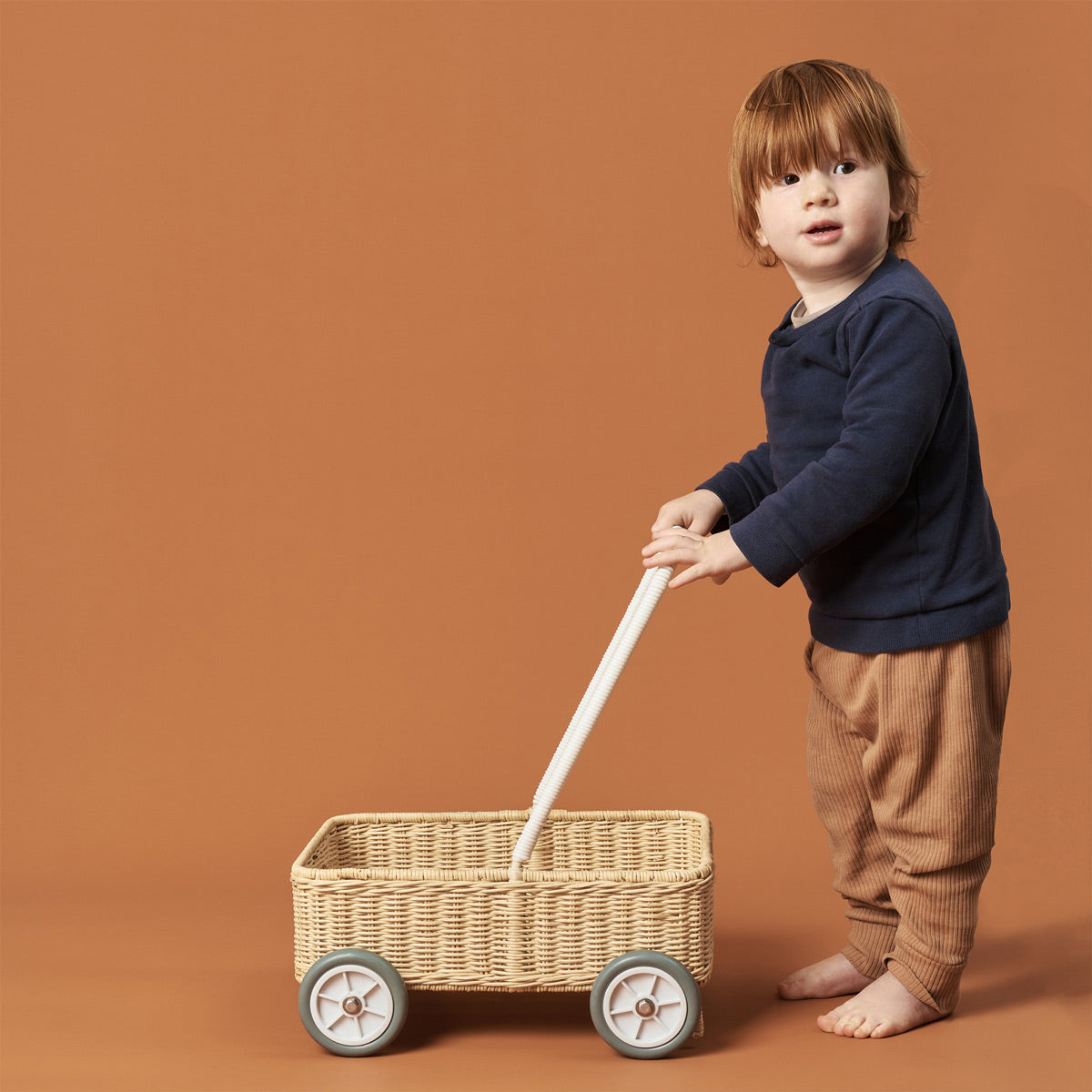 Young boy stood holding the Olli Ella Wamble Walker