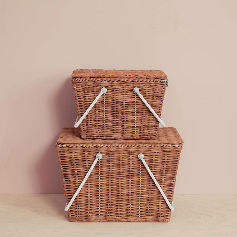 a rattan picnic basket with white handles