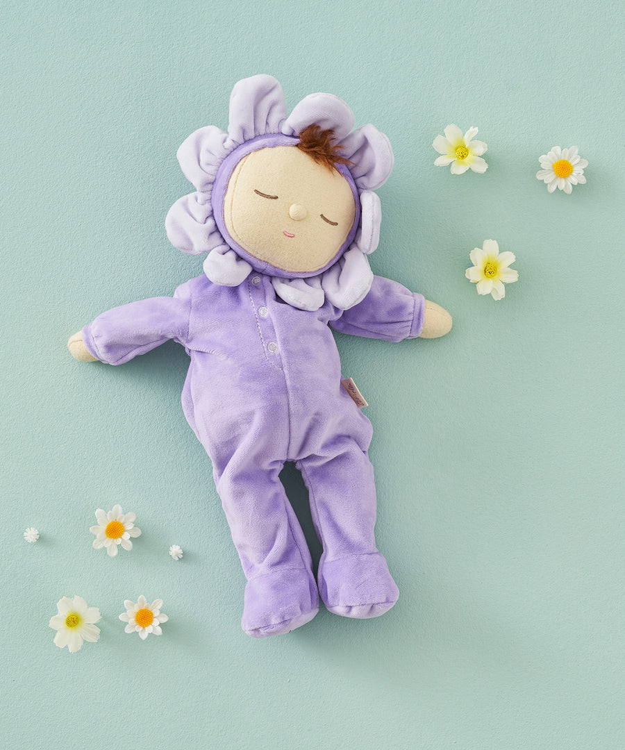 Olli Ella Lavender Pickle Dozy Dinkum Doll laying on a green surface surrounded by little white flower heads. 