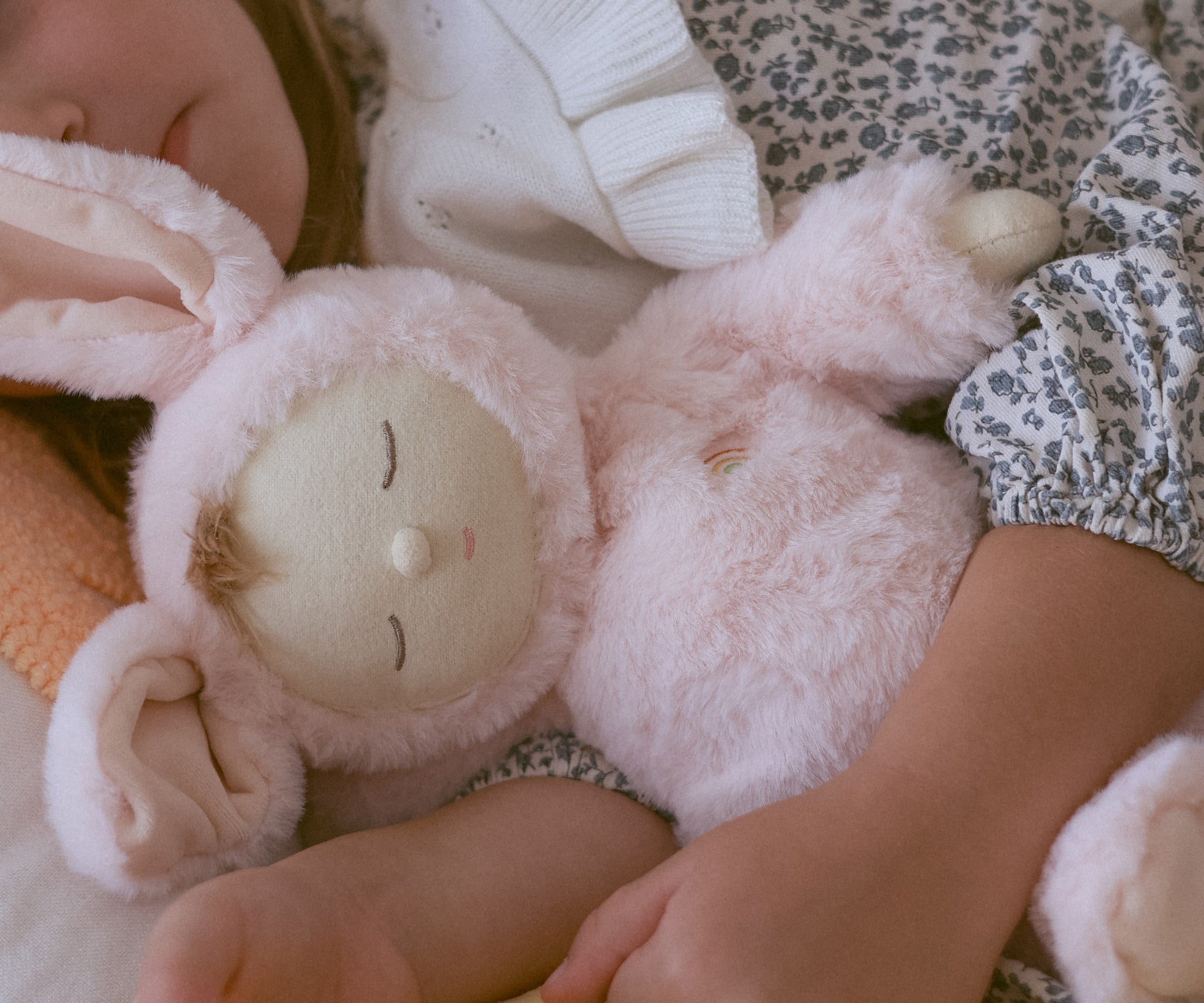 A close of a child cuddling the Olli Ella Pink Bunny Moppet Lullaby Cozy Dinkum.