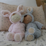 Two Olli Ella Lullaby Cozy Dinkums placed on a bed. 