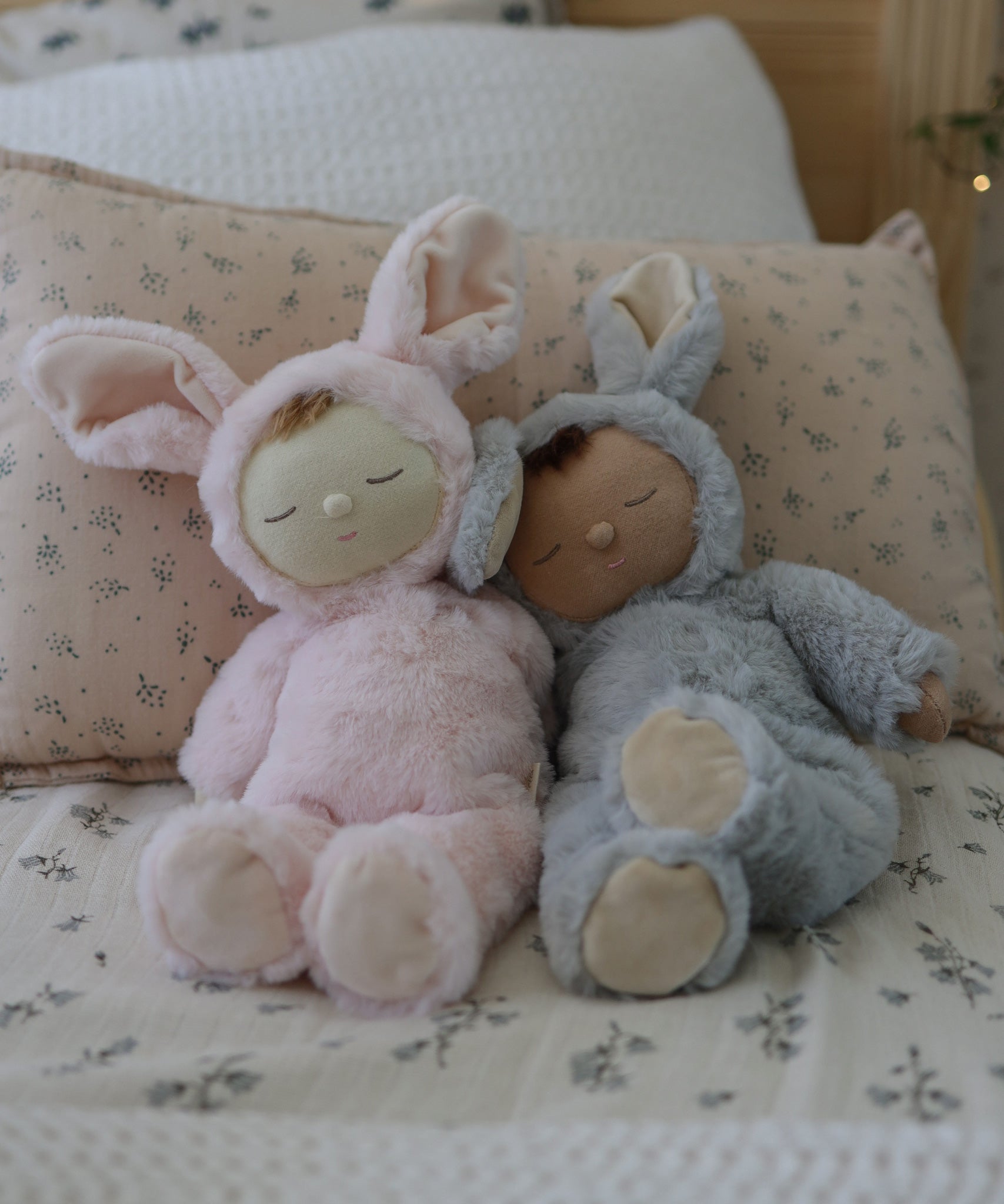 Two Olli Ella Lullaby Cozy Dinkums placed on a bed. 