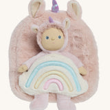 A OIli Ella pink fluffy unicorn backpack with a rainbow on the front  with a dinky dinkum doll sitting on the bag on a cream background.