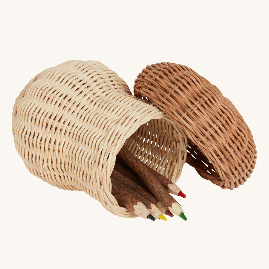 An Olli Ella Porcini basket on it's side with the the lid open. Wooden twig pencils can be seen inside