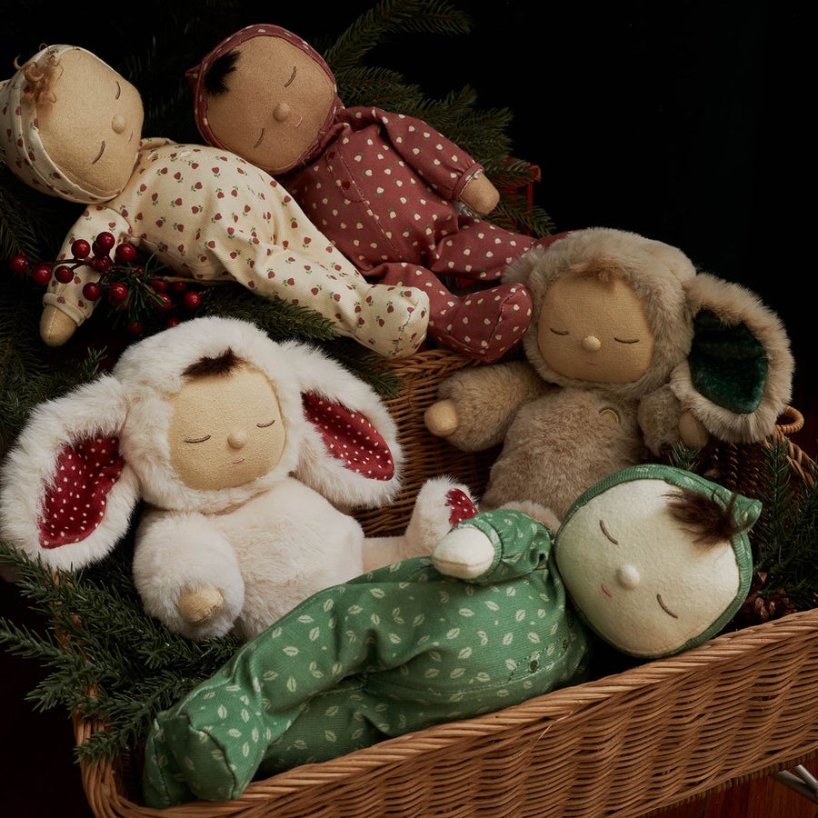 A child wearing pink playing with three Dozy Dinkum dolls including Olli Ella Dozy Dinkum Pudding in a pale green outfit