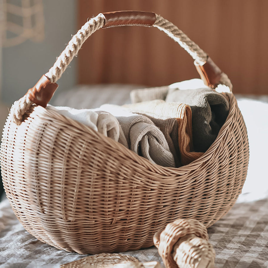 Close up of person holding the Olli Ella woven rattan half moon basket under their forearm