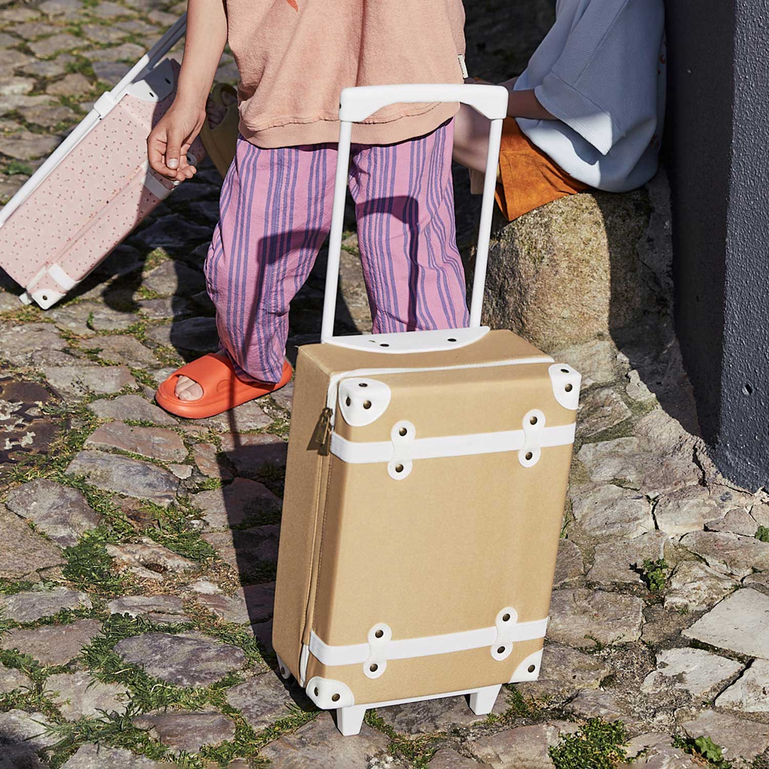 Child holding a lion cozy dinkum sat down next to a open See-Ya suitcase filled with things including the matching butterscotch See-Ya wash bag