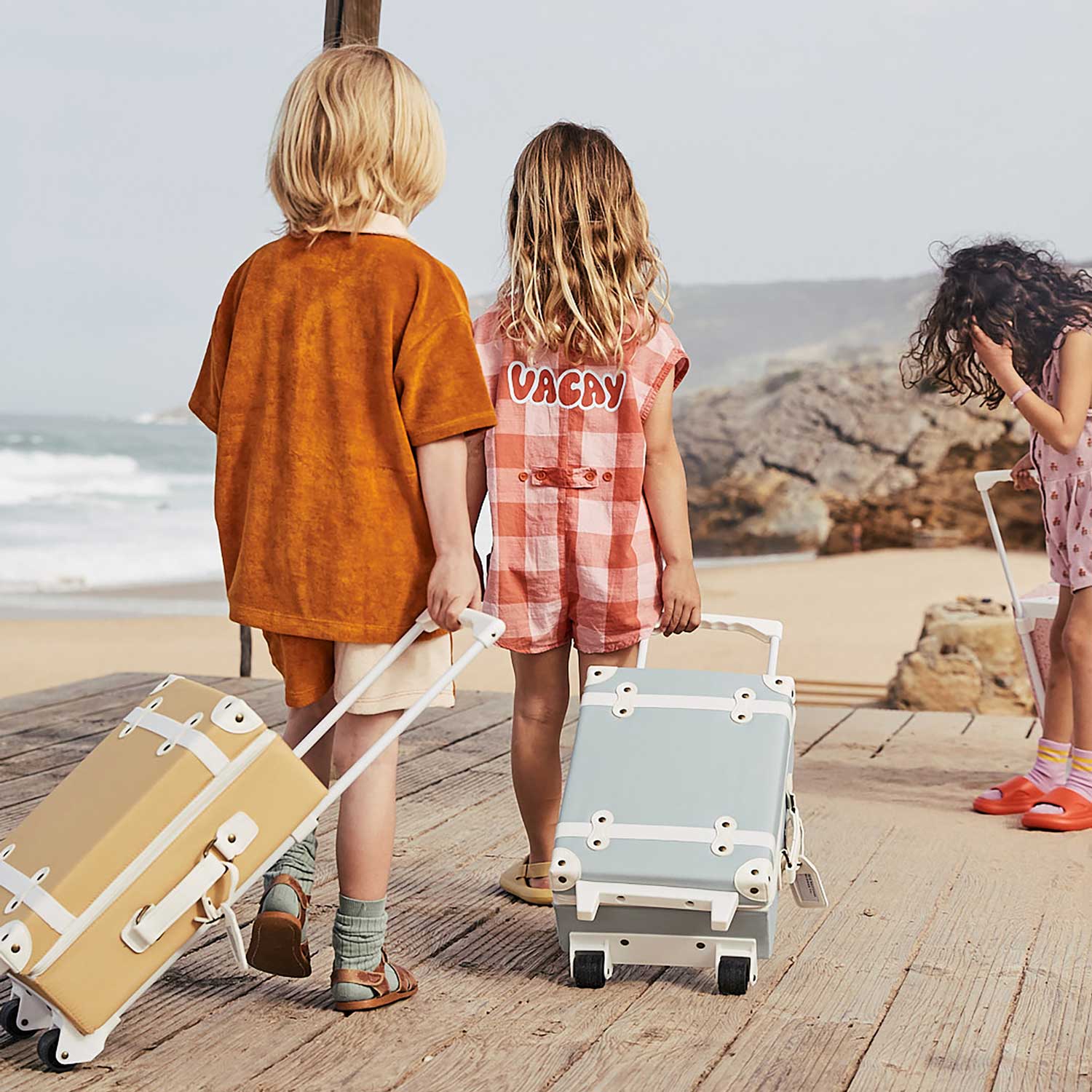 Child leaning on their butterscotch coloured See-Ya suitcase