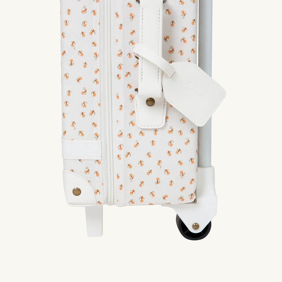 Close up of the tag on the Olli Ella See-Ya Suitcase with a Leafed Mushroom print  pictured on a plain background