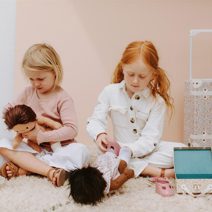 2 girls sat on the floor playing with the Olli ella dinkum dolls