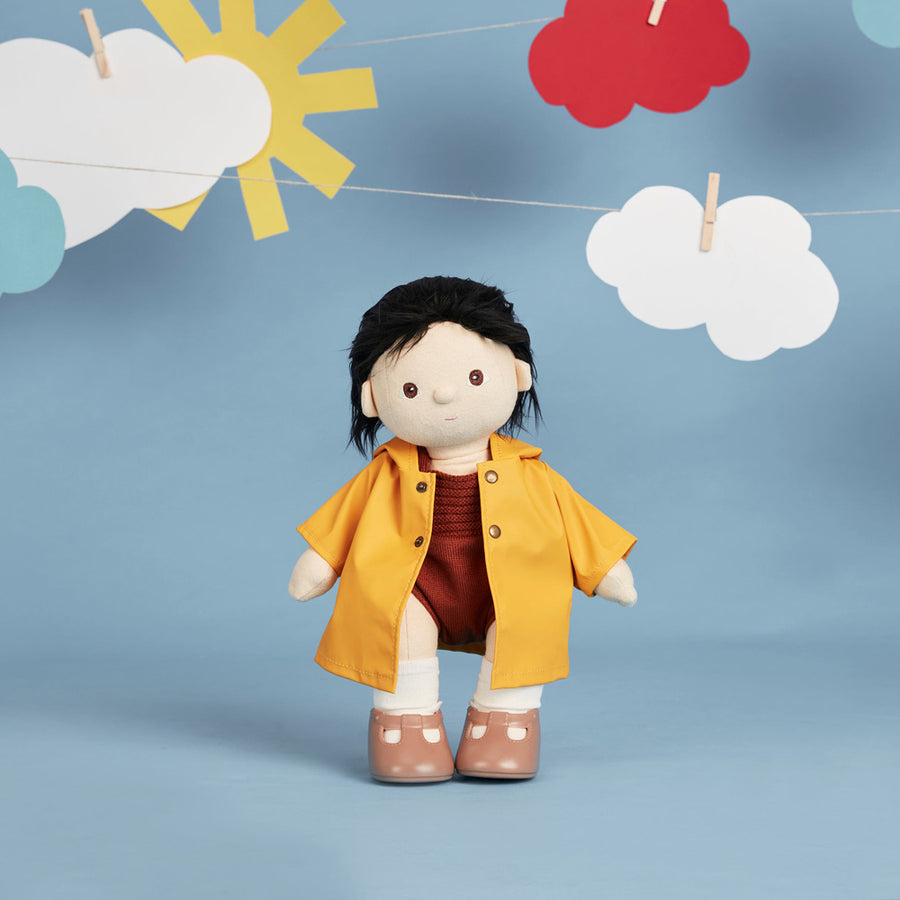 Olli Ella dinkum doll toy stood on a white background wearing the ahoy dress up raincoat in yellow