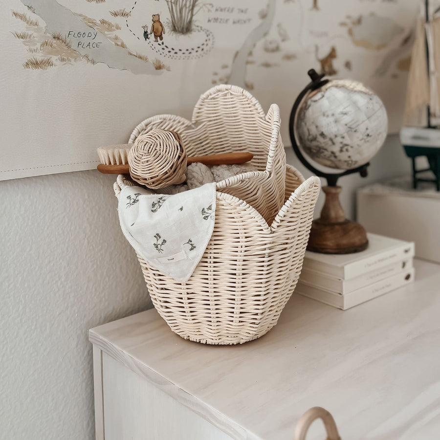 The Olli Ella Rattan Lily Basket Set in Buttercream on a chest of draws in a nursery