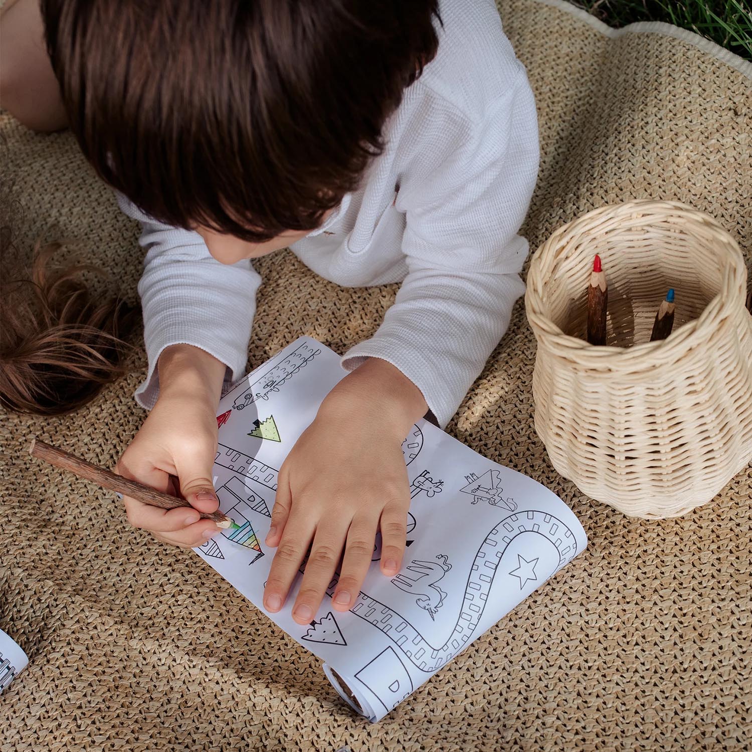 A child colours in the Olli Ella Playpa Children's Colouring Paper Roll Travel Pack  -  Fairytale Design in an outdoor setting.