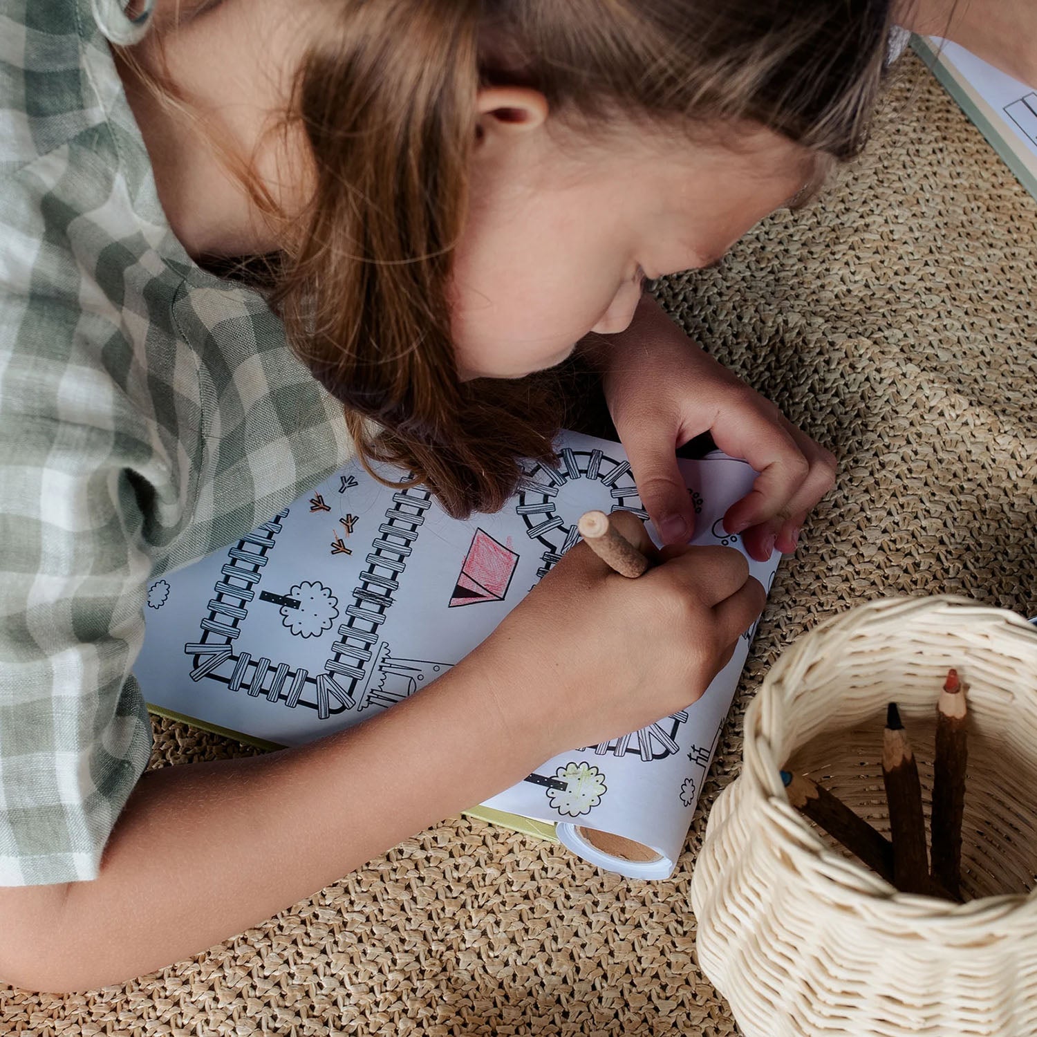 A child plays with the Olli Ella Playpa Children's Colouring Paper Roll Travel Pack  -  Forest Design in a home setting.