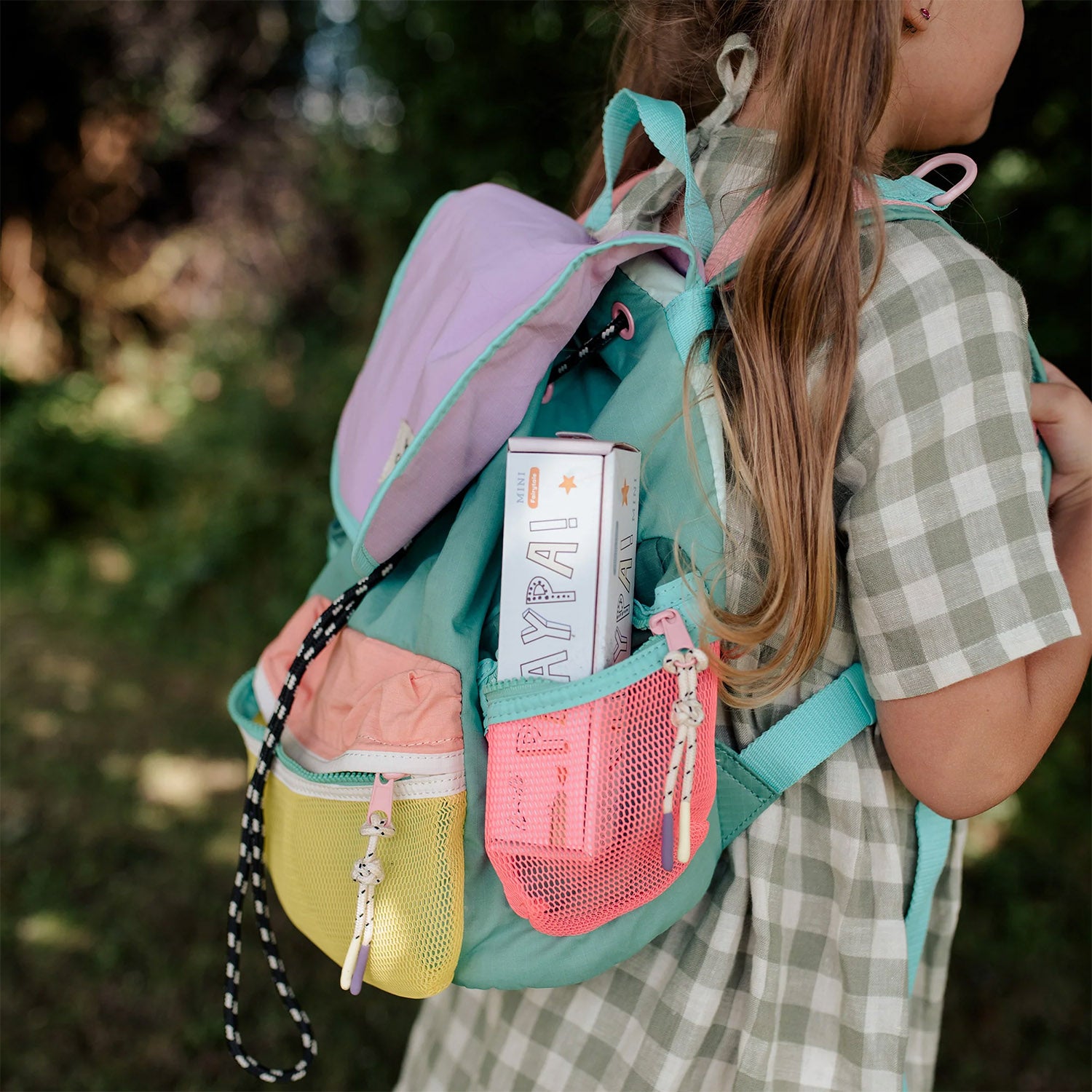 A child carries the Olli Ella Playpa Children's Colouring Paper Roll Travel Pack  -  Fairytale Design in her backpack whilst outdoors.