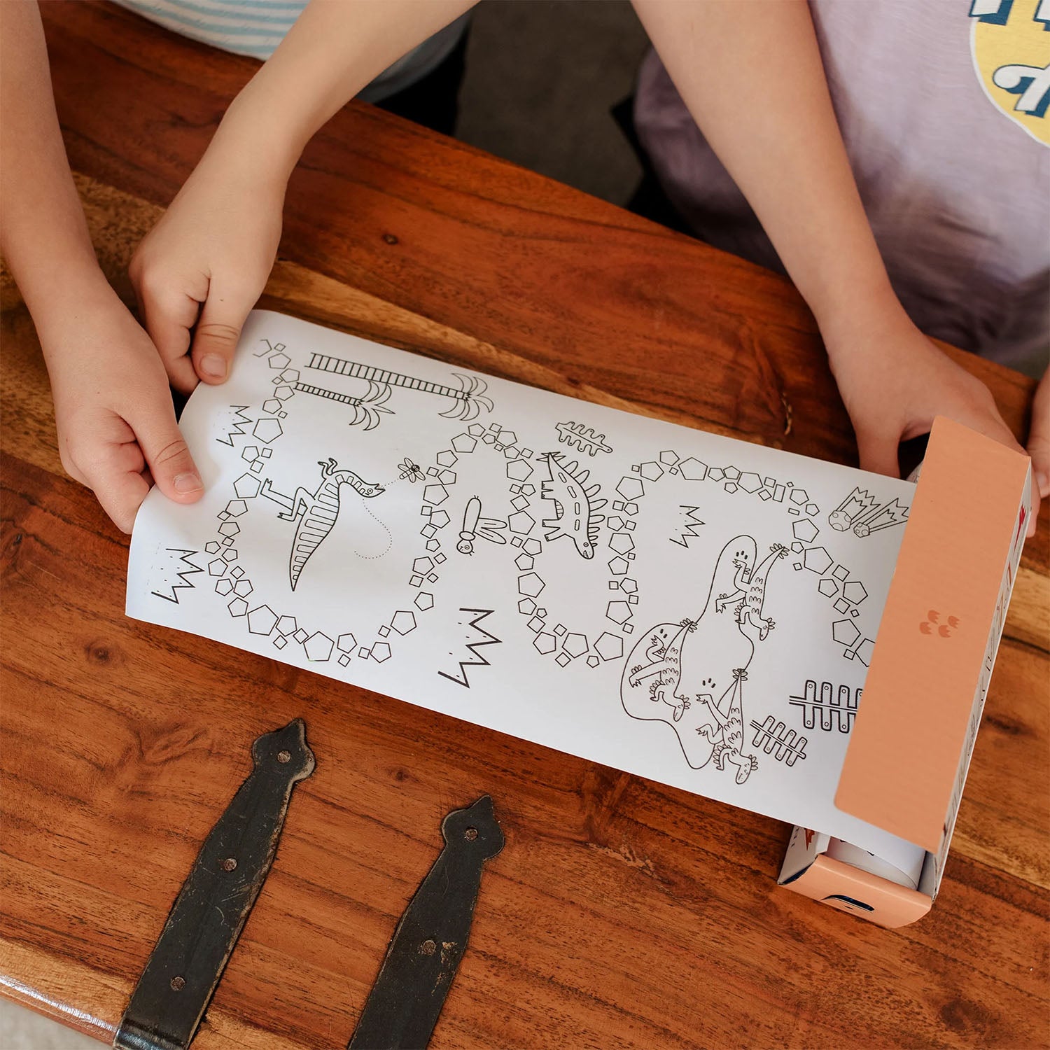 Two children roll out the colouring sheet from the Olli Ella Playpa Mini Pack Dino.