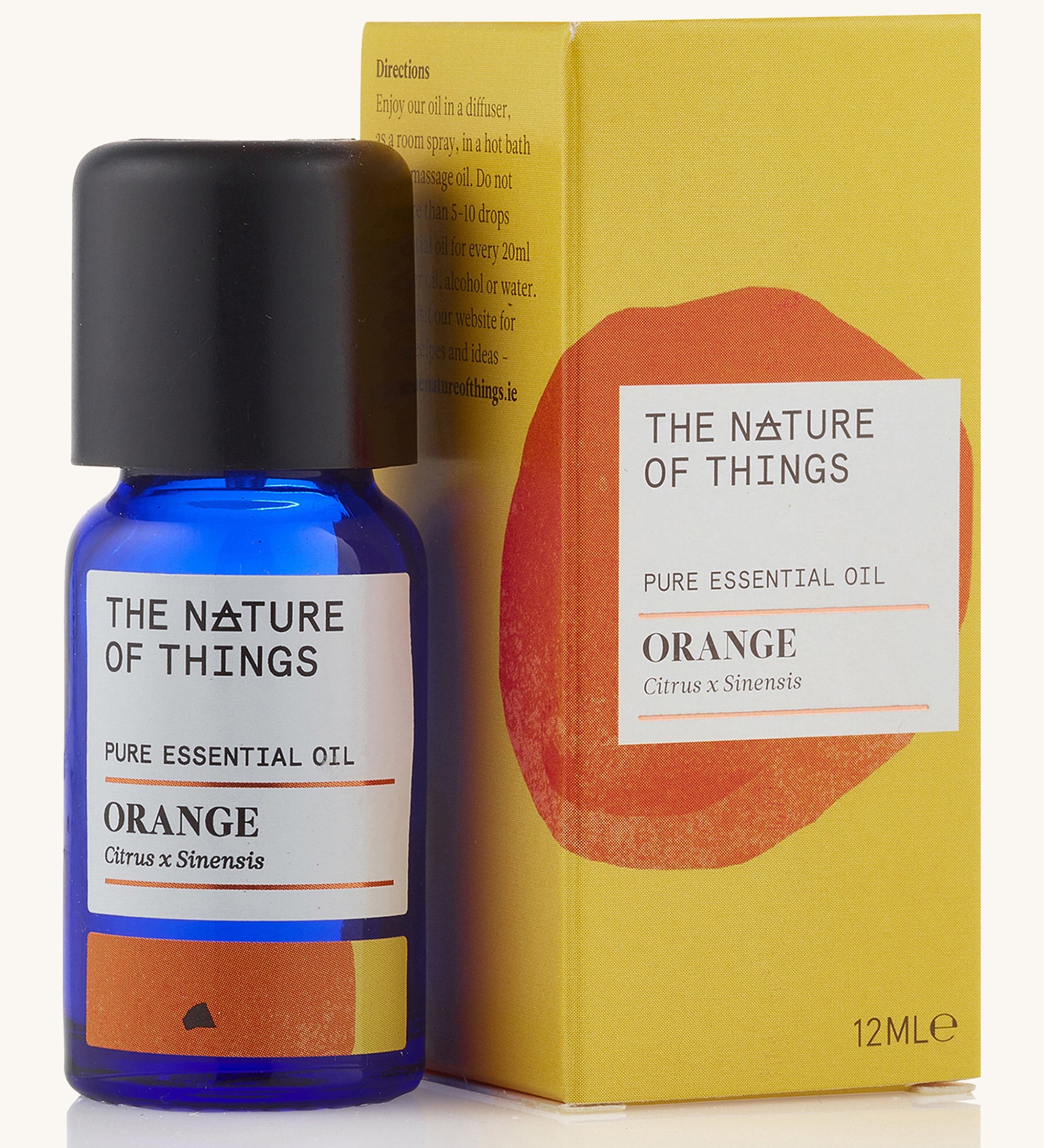 Orange pure essential oil in a blue glass bottle in front of a decorative yellow cardboard box.