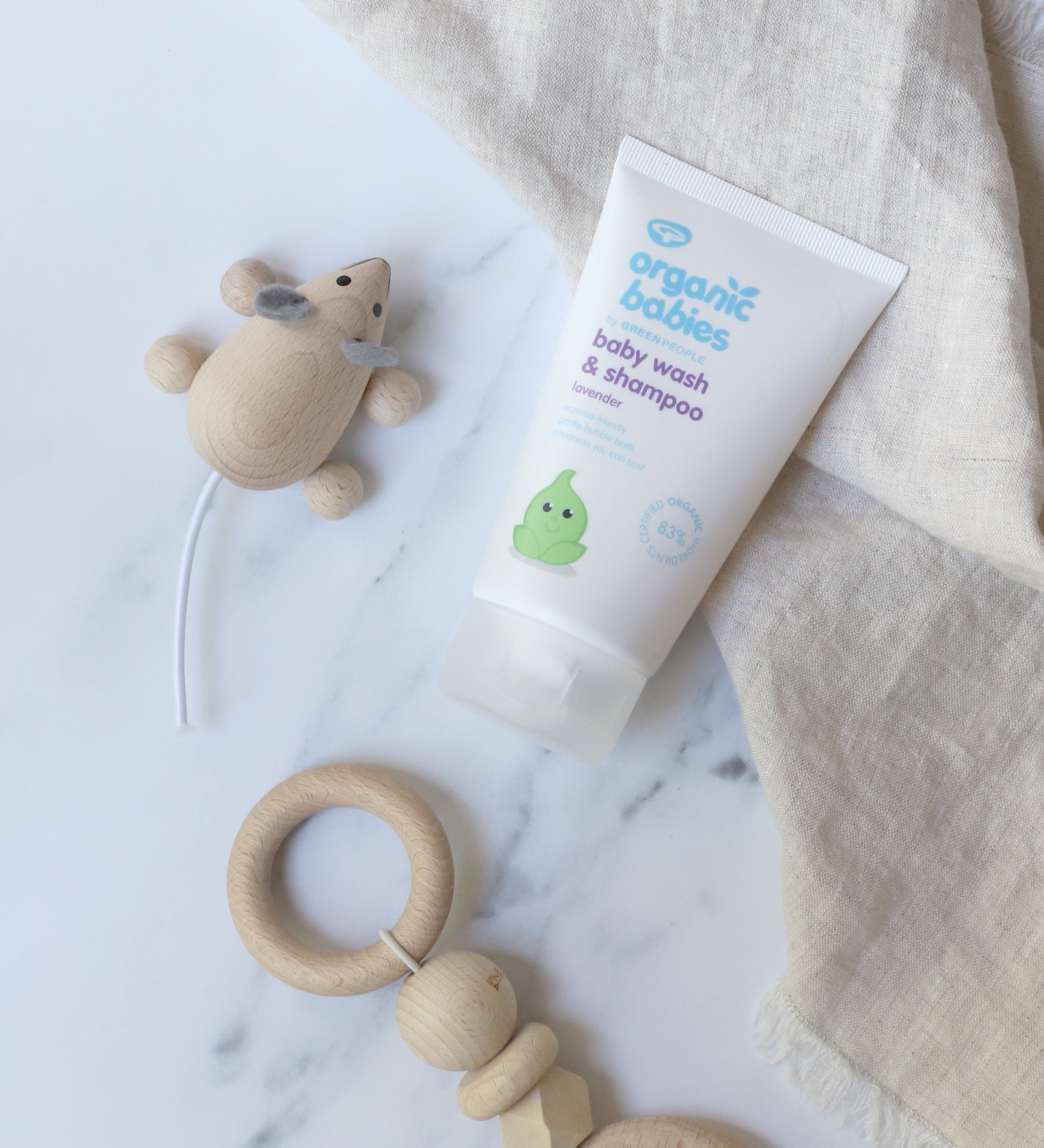 Organic Babies Baby Wash & Shampoo Lavender on a marble surface next to a wooden toy mouse and teething toy.