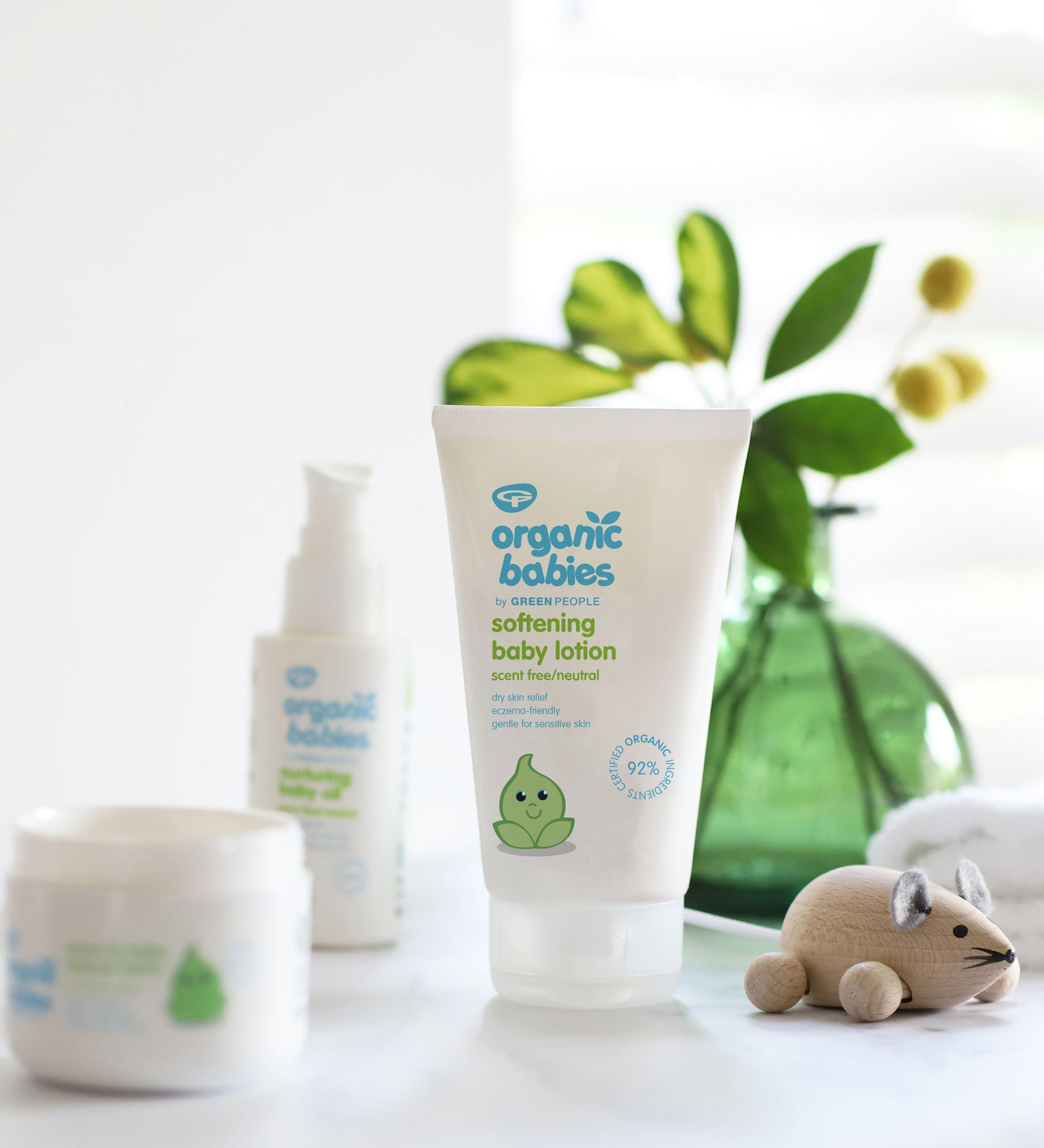 Organic Babies Softening Baby Lotion 150ml in front of a green vase with leaves in. 