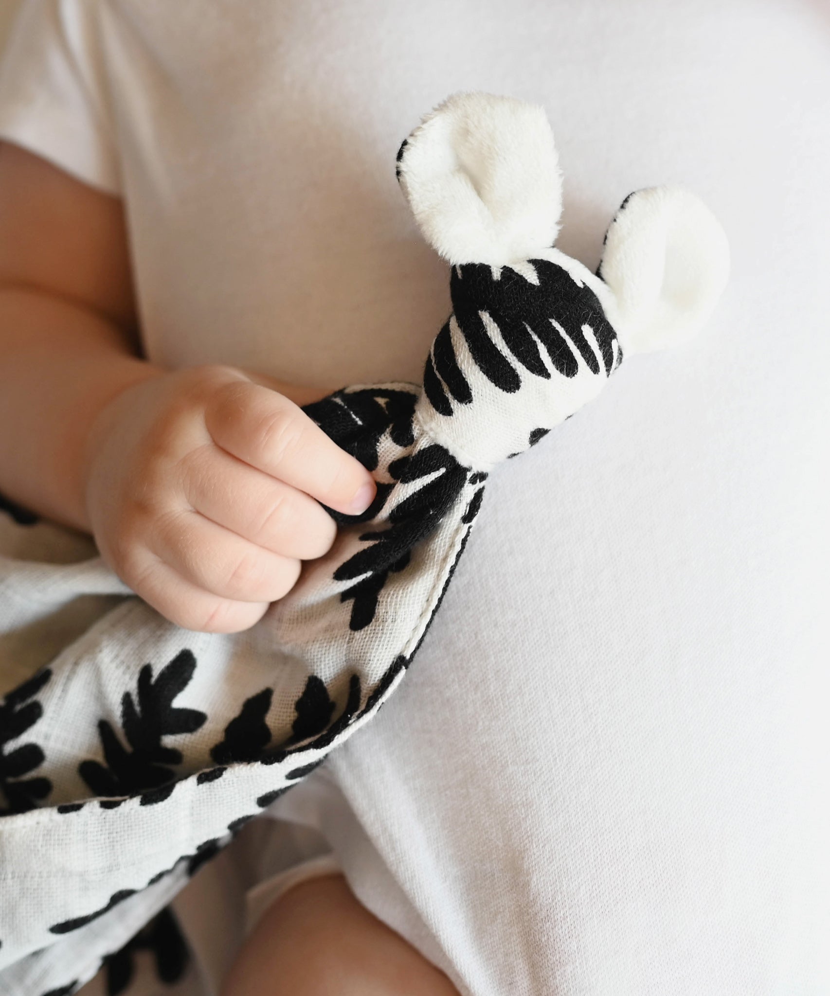 A baby holding the Etta Loves Organic Cotton Baby Comforter - Fern