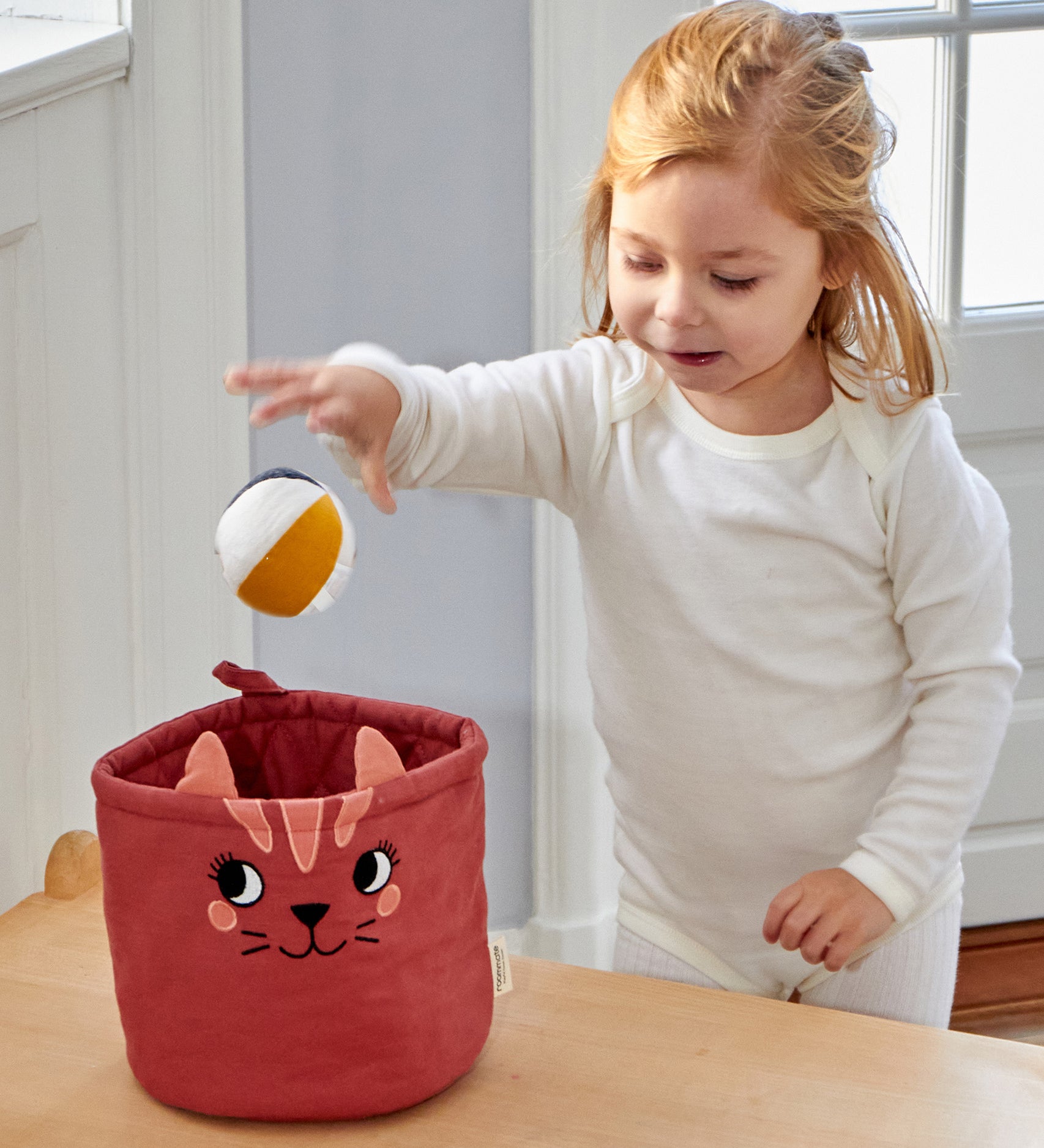 A child putting a Roommate Canvas Ball into the mini cat basket