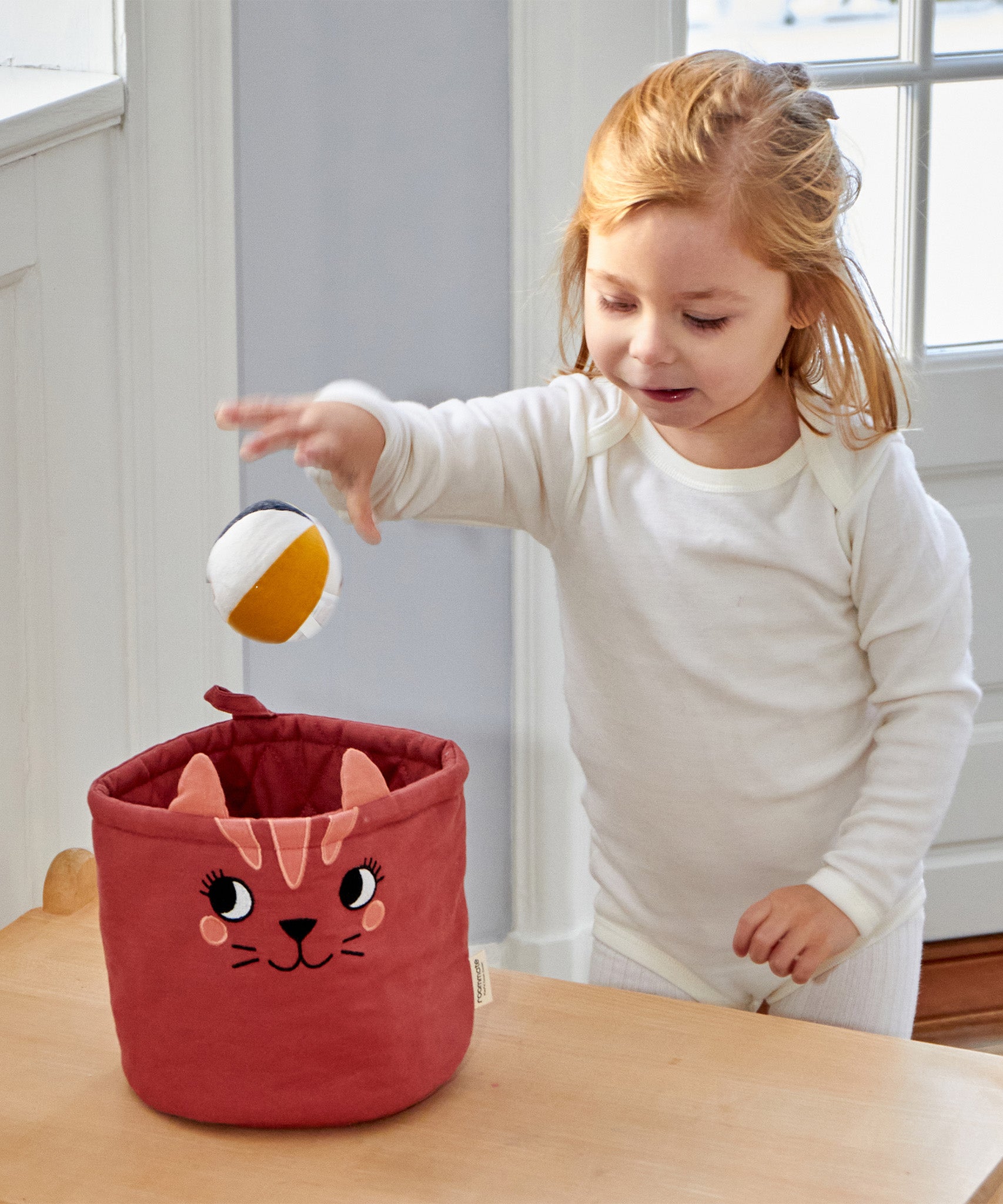 A child putting a Roommate Canvas Ball into the mini cat basket