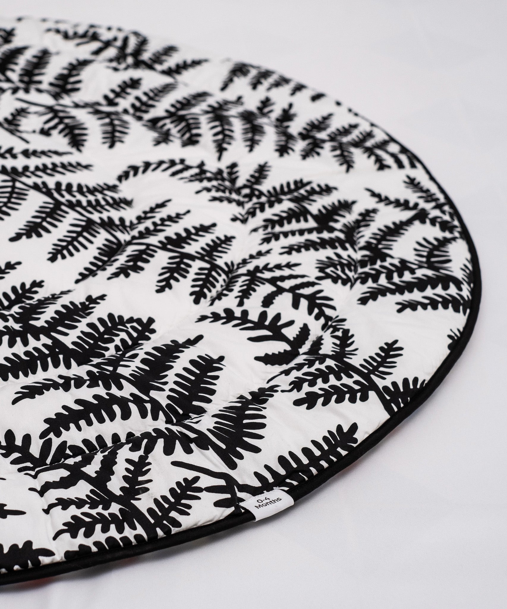 A baby looking and enjoying and looking at the black and white Fern side of the Etta Loves Reversible Organic Cotton Baby Play Mat - Plant Print 