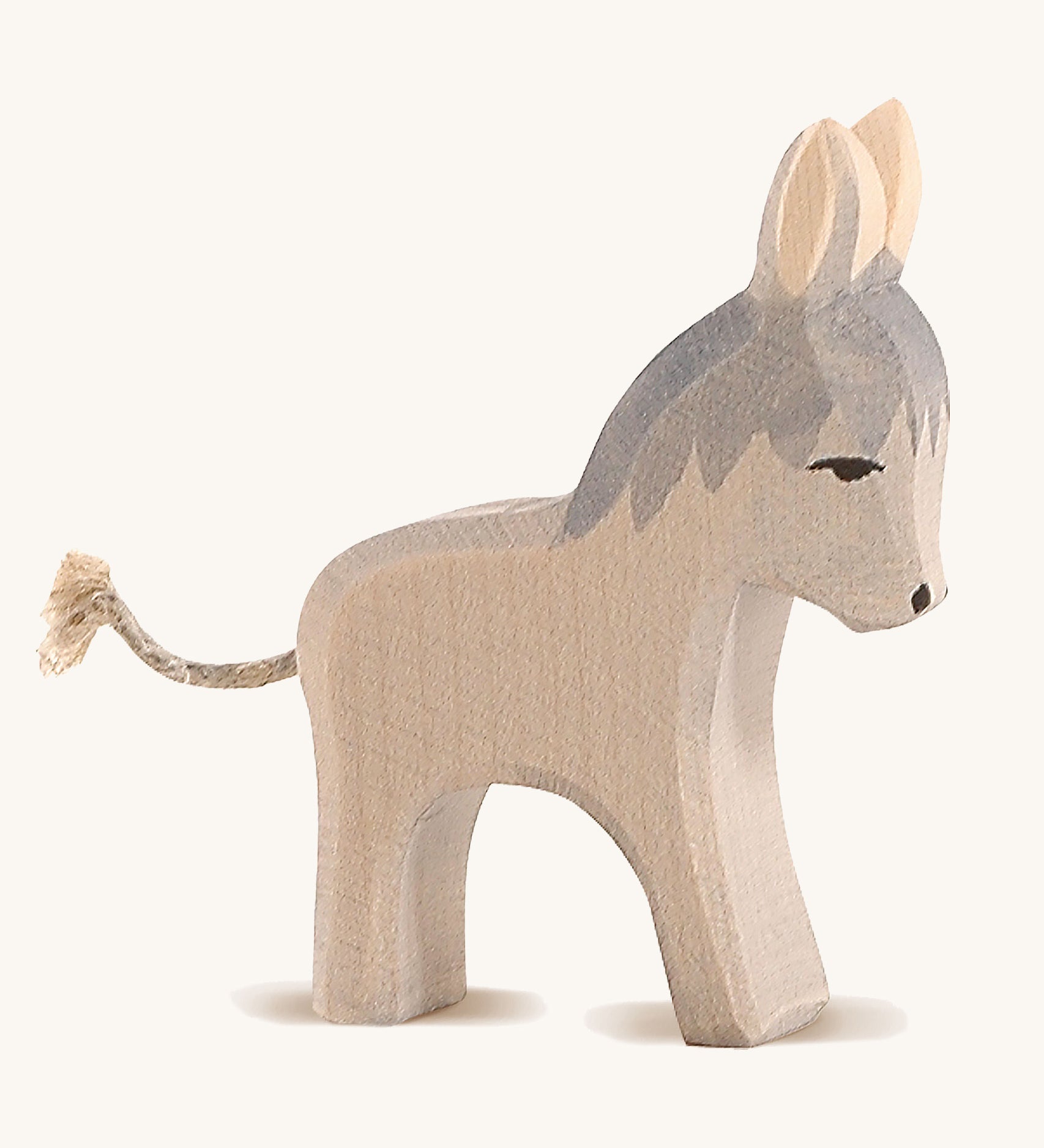 A grey wooden small standing Ostheimer donkey figure on a cream background.