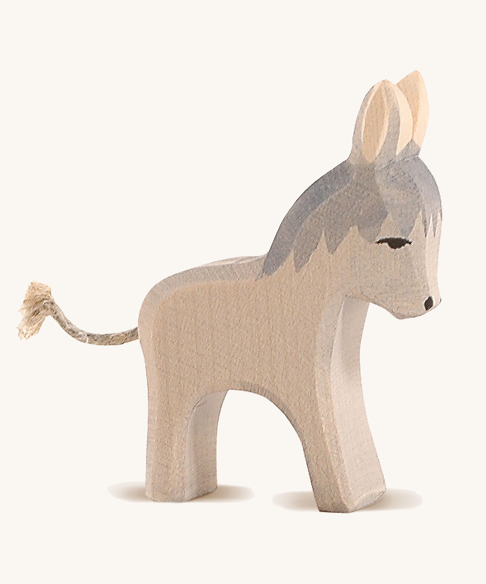 A grey wooden small standing Ostheimer donkey figure on a cream background.