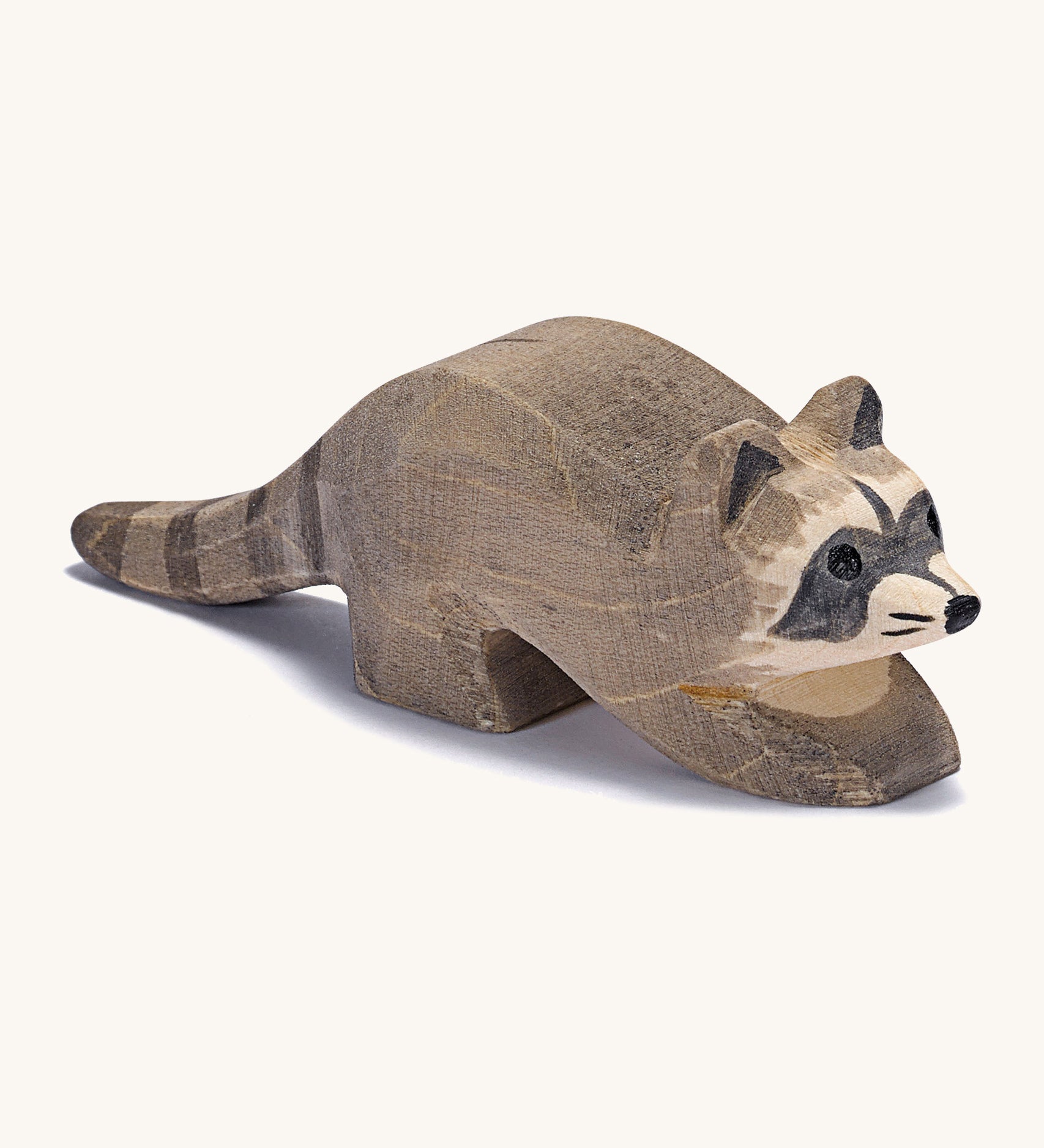 A small wooden Ostheimer racoon figure on a cream background.