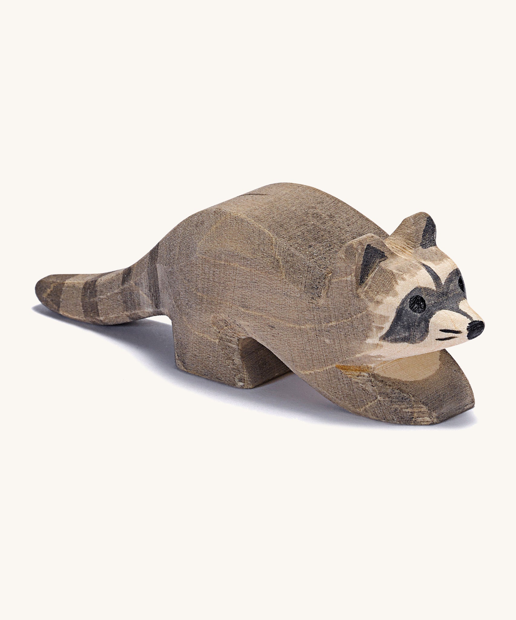 A small wooden Ostheimer racoon figure on a cream background.