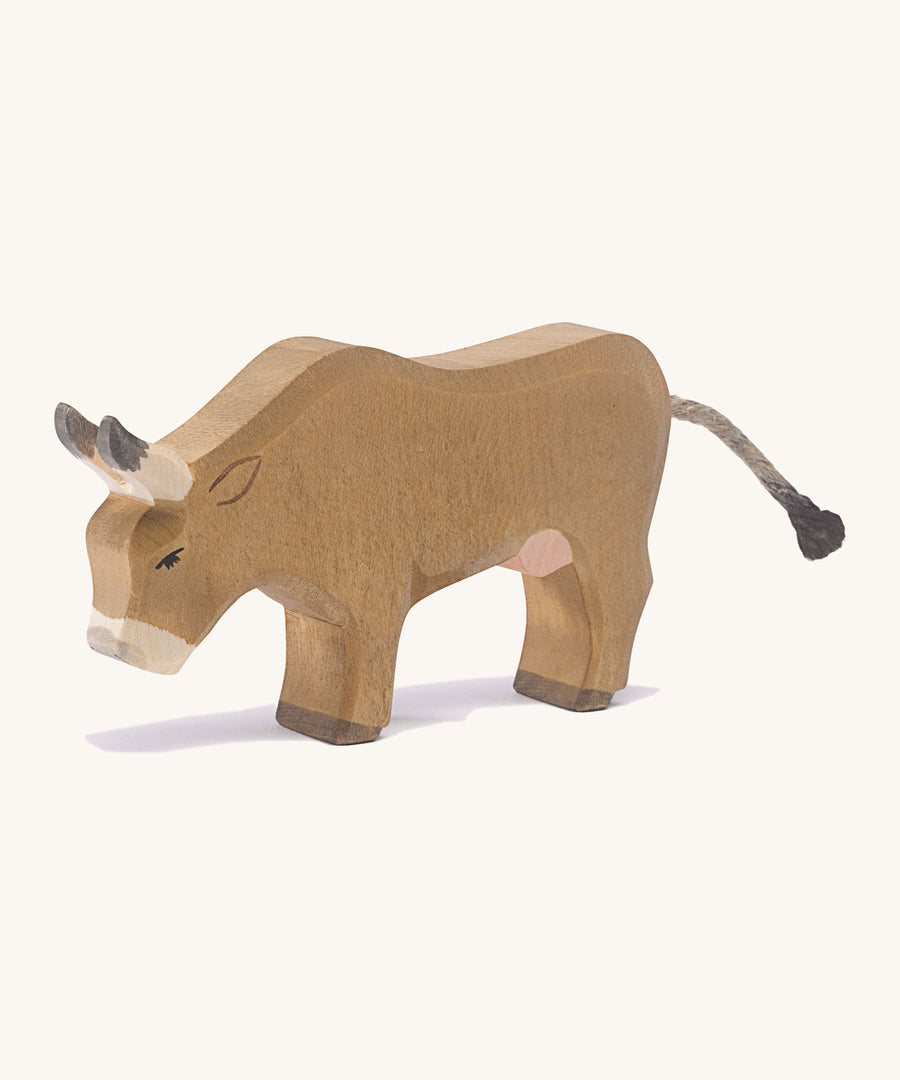 A wooden OStheimer alp cow eating on a cream background.