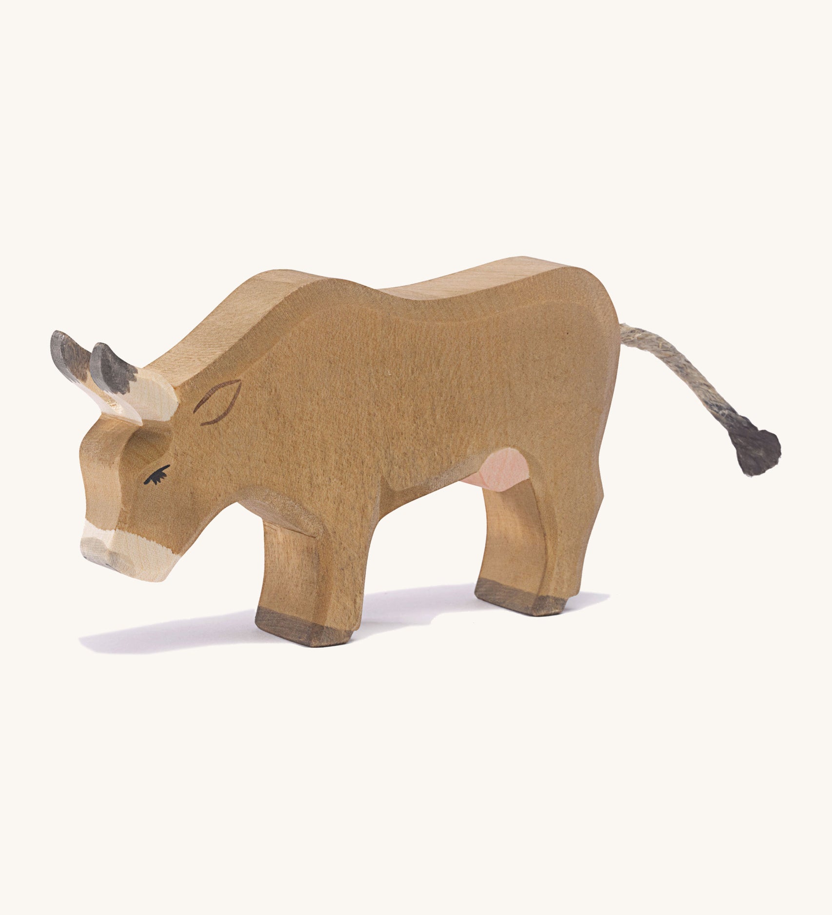 A wooden OStheimer alp cow eating on a cream background.