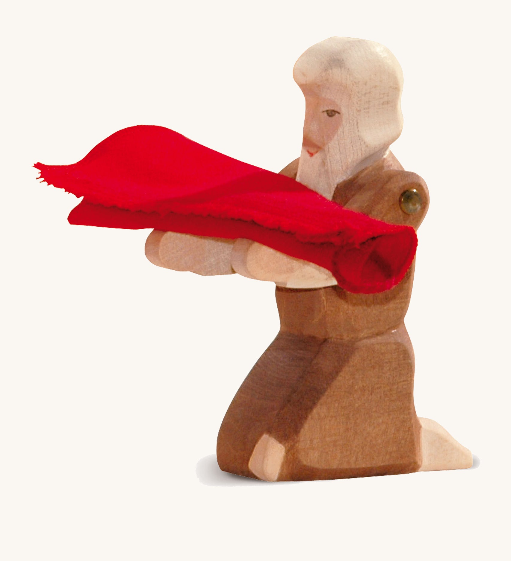 A kneeling wooden beggar figure holding a piece of red cloth on a cream background