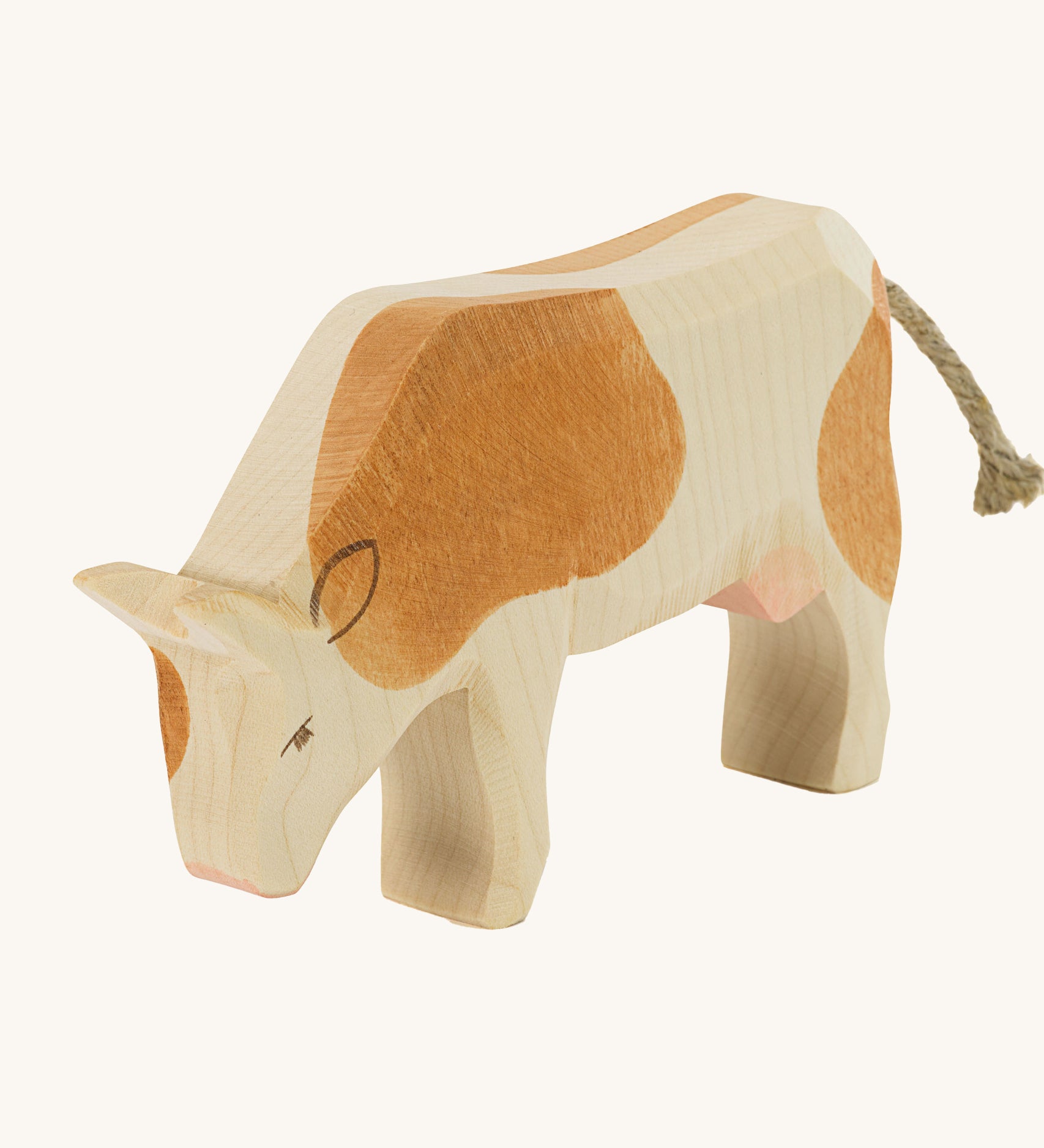 Ostheimer Brown Cow Eating wooden toy figure on a plain background. 