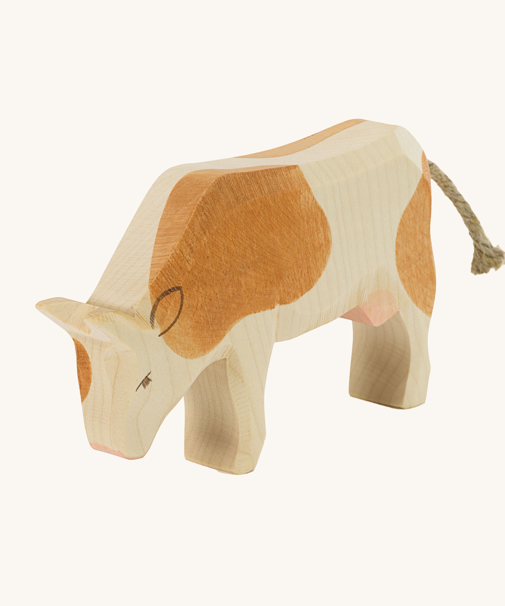 Ostheimer Brown Cow Eating wooden toy figure on a plain background. 