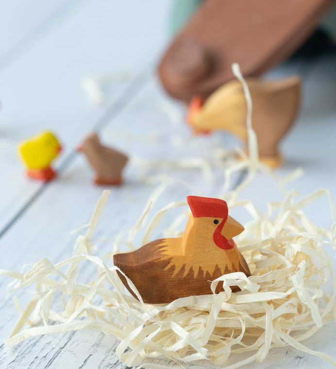 Ostheimer Brown Hen on Nest figure pictured on wood wool nest. Other Ostheimer figures can be seen in the background. 