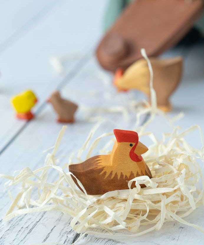 Ostheimer Brown Hen on Nest figure pictured on wood wool nest. Other Ostheimer figures can be seen in the background. 