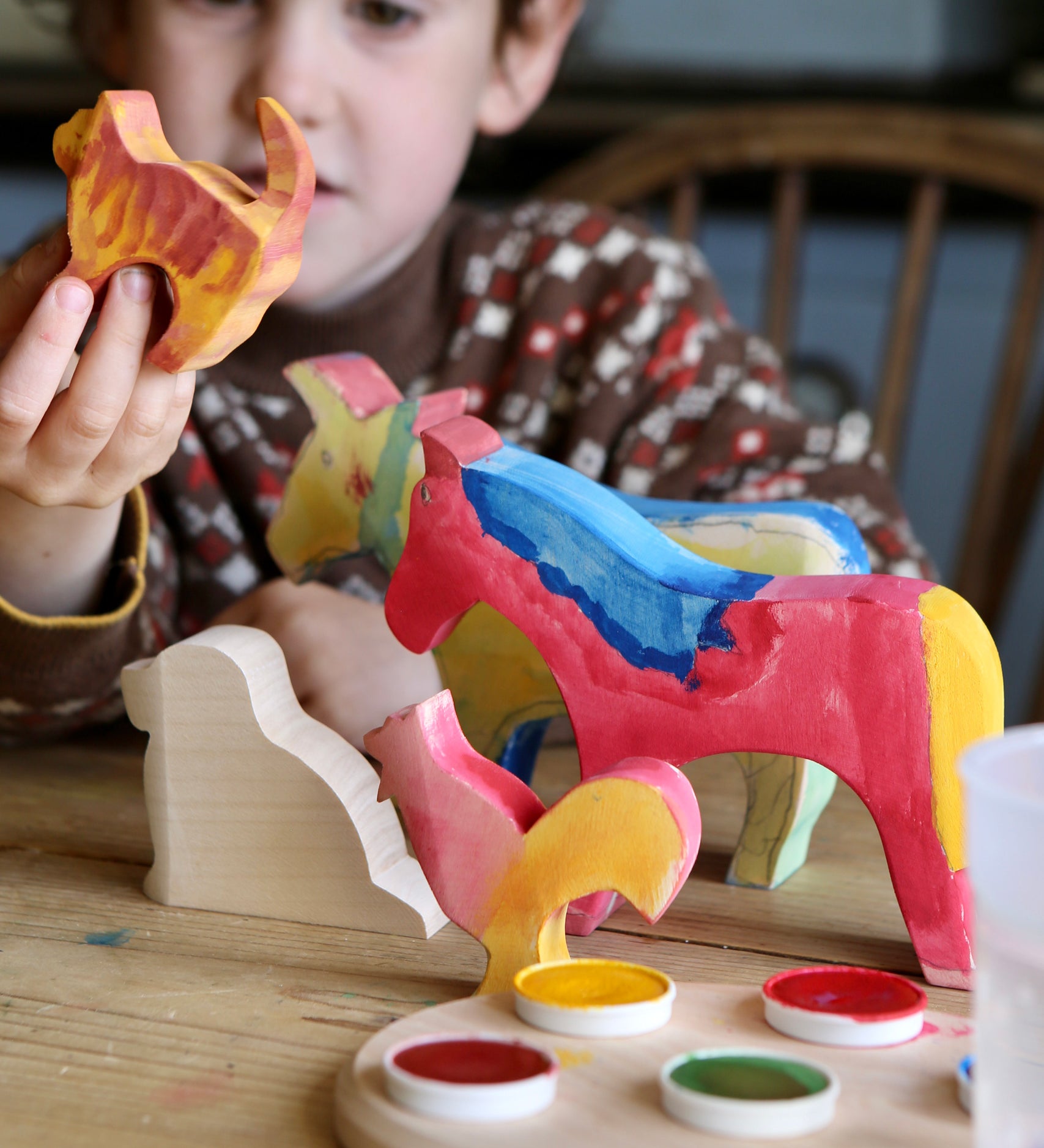 A child with the figures from the Ostheimer creative set in front of them. Some have been painted. 