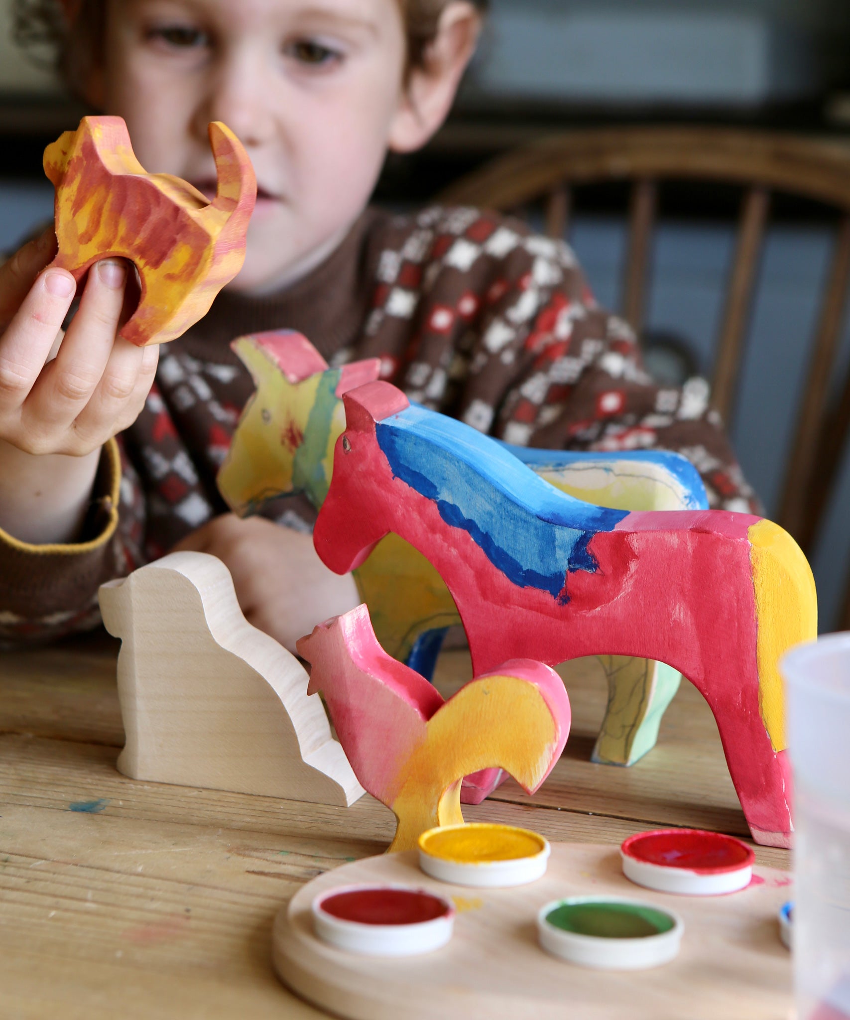 A child with the figures from the Ostheimer creative set in front of them. Some have been painted. 